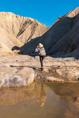 A young woman walking along the water in the desert on a trek in the Travertino waterfall and Rambla de Otero in the desert of Tabernas, Almería province, Andalusia