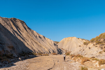A young hiker with backpack and hat in the desert of Tabernas, Almería province, Andalusia. On a trek in the Rambla del Infierno