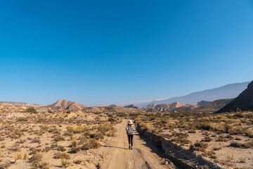 A young woman walking along the water in the desert on a trek in the Travertino waterfall and Rambla de Otero in the desert of Tabernas, Almería province, Andalusia