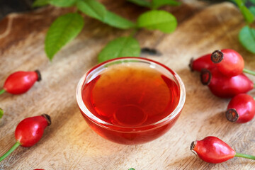 A bowl of rosehip seed oil with fresh rosehips