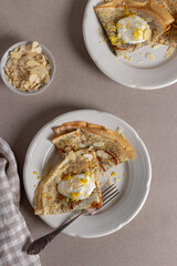 Crepes, thin pancakes with poppy seeds, lemon and sour cream on brown background. Healthy breakfast in sunny morning .