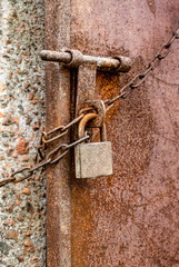 Abandoned old rustic lock with a chain on a metal door close up shot