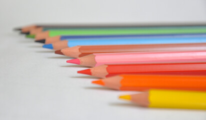several colored pencils on a white background