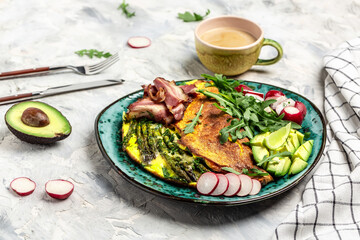 Stuffed egg omelette with vegetable, asparagus, fried egg, avocado, arugula, bacon ham and cheese. Low carb diet concept. high fat diet