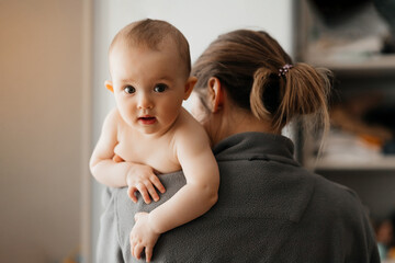 Home photo of mum holding infant child on hands. Mother hugging her little 5 months old daughter. Loving mom carying of her newborn baby. Copy space