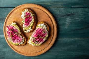 Healthy breakfast toasts from sliced watermelon radish or chinese daikon with goat cheese, microgreen and chia seeds, Food recipe background. space for text. top view