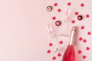 Creative trendy flat lay with pink champagne bottle and flutes, red glass hearts and chocolate...