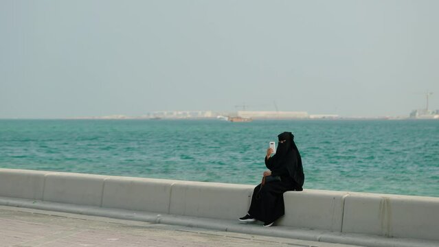 Woman in burqa uses smartphone at Doha Qatar
