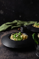 Pasta with spinach sauce on a black plate