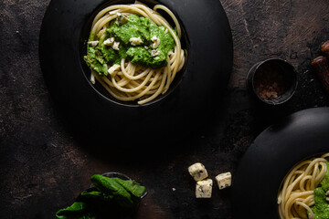 Pasta with spinach sauce on a black plate