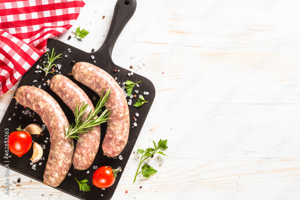 Wall mural Bratwurst or sausages on cutting board at white wooden table. Top view with copy space.