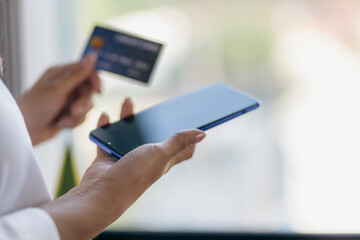 Hand holding credit card and using mobile phone.