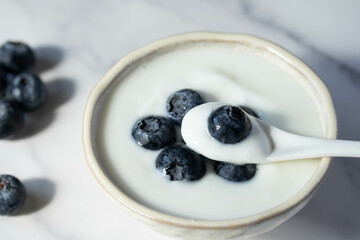 fresh blueberry yogurt in white cup on marble background