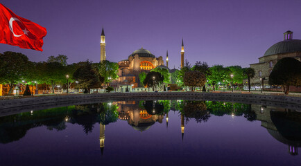 Fototapeta na wymiar Hagia Sophia Mosque under purple sky and Turkish flag in Istanbul