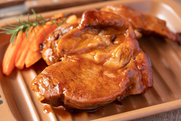 Meat during grilling. Chuck steak and rosemary garnished carrots.