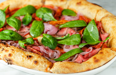 Pizza with roast beef, sundried tomatoes, pickled onion and spinach. Italian cuisine
