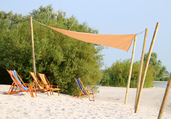 Deckchairs under shade sail at the beach - summer scene (Hindeloopen, Frisia, Netherlands) - 482859086