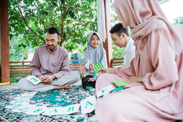 Asian father, mother and children making eid mubarak greeting cards