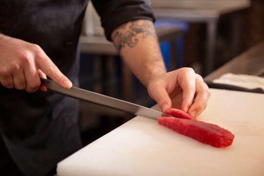 Anonymous chef cutting fish in kitchen