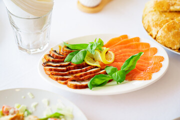 white plate with meat cuts. assorted salted meat with lemon and herbs.