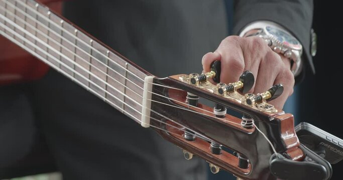 Asian man hands tuning acoustic guitar strings before playing music at home
