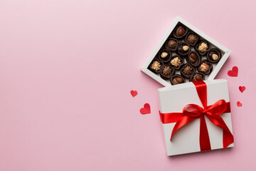Delicious chocolate pralines in red box for Valentine's Day. Heart shaped box of chocolates top view with copy space - obrazy, fototapety, plakaty