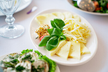 a white plate with sliced cheese. assorted.