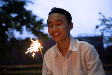 Smiling boy lighting fireworks at night during the celebration
