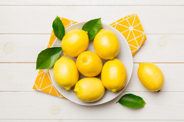Fresh cutted lemon and whole lemons over round plate on colored background. Food and drink ingredients preparing. healthy eating theme top view vith copy space