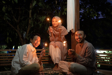 The family celebrates Eid Mubarak at night by burning fireworks - obrazy, fototapety, plakaty