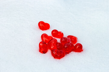 Set of small bright red glass hearts on powdery snow of snowdrift at cold winter day, symbol of...