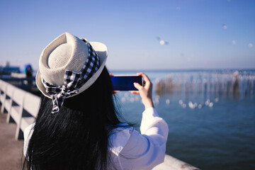 girl relaxing taking pictures of the sea and birds