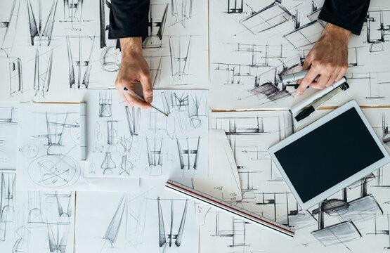 Table Top View of Designer Hands Drawing Blueprint Design on a Table with Digital Tablet and Sketches at Design Studio