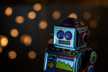 Fototapeta premium Close-up of a colorfull tin robot with lights out of focus behind.