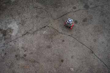 Colorful tin robot seen from above walks through concrete field.