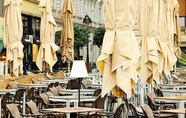 Obraz na płótnie Canvas Street cafe tables on a rainy autumn day and collected umbrellas 