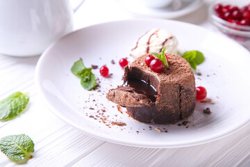 Fototapeta na wymiar Chocolate fondant with ice cream, cranberries and mint on a white plate
