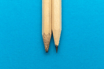 New and old pencil on a blue background.