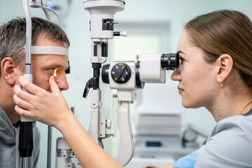 Ophthalmologist and patient testing eyesight. Man doing eye test with optometrist. Ophthalmologist using apparatus for eye examination in clinic. Doctor examining patient doing eyesight measurement