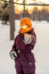 Fototapeta na wymiar cute girl keeps a sparkler in winter in forest