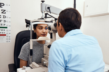 Fototapeta na wymiar Can't see Come to me. Shot of a young woman getting her eyes examined with a slit lamp by an optometrist.