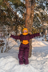 Fototapeta na wymiar cute girl in winter jumpsuit walks in the park in winter