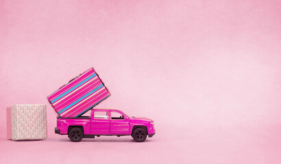 Pink toy truck with gift boxes. Concept of gifts, sale, love