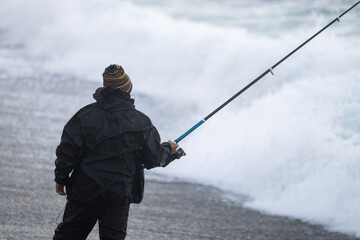 Unrecognizable man with a wool cap fishing on a cold and bad weather day