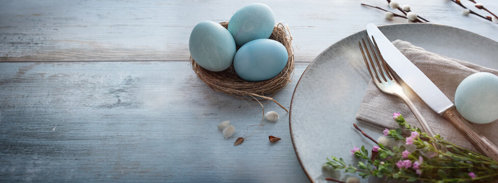 Easter breakfast decoration with spring flowers on bright wood. Horizontal easter background with space for text.