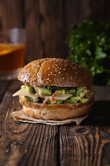 Vegan burger with avocado on rustic wooden background.