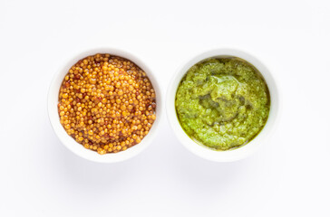 Sauce set - pesto and mustard seeds in gravy bowls isolated on white background