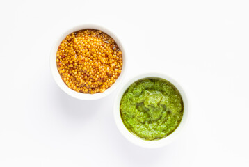 Sauce set - pesto and mustard seeds in gravy bowls isolated on white background