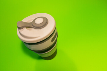 Reusable silicone cup for coffee on a green background.