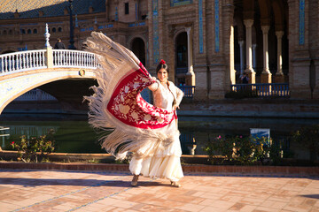 Flamenco dancer, woman, brunette and beautiful typical spanish dancer is dancing with a red manila...